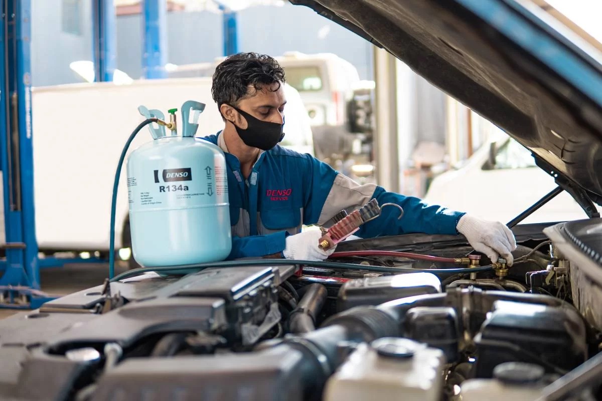 Técnico realizando carga de refrigerante R134a en sistema de climatización vehicular